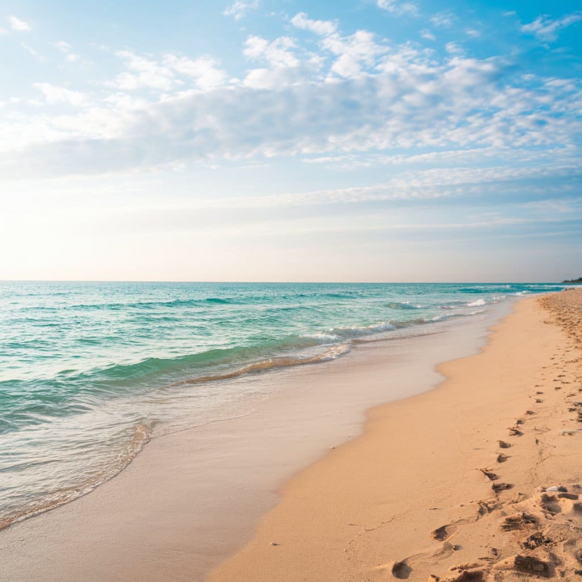 Spiaggia di sabbia dorata in una delle migliori destinazioni balneari in Italia, con mare calmo e cielo sereno.